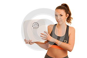 Beautiful young active fit woman hold scale as gesture of loosing weight isolated over white background - weight loss