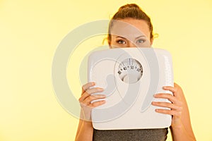 Beautiful young active fit woman hold scale as gesture of loosing weight isolated over white background - weight loss