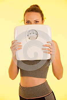 Beautiful young active fit woman hold scale as gesture of loosing weight isolated over white background - weight loss