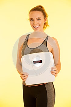 Beautiful young active fit woman hold scale as gesture of loosing weight isolated over white background - weight loss