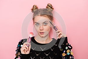 Beautiful young adult woman doing makeup using Mascara and powder brush
