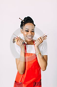 Beautiful young African American beautician woman holding set of make up brushes.