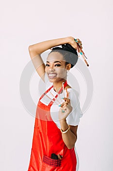Beautiful young African American beautician woman holding set of make up brushes.