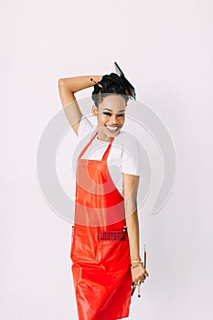 Beautiful young African American beautician woman holding set of make up brushes and eye-shadows, isolated on white