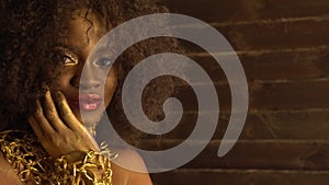 Beautiful young african american female model with gold glossy makeup. Face art. Black studio background