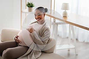 Beautiful young african american pregnant woman embracing her big belly