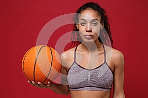 Beautiful young african american sports fitness basketball player woman in sportswear working out isolated on red