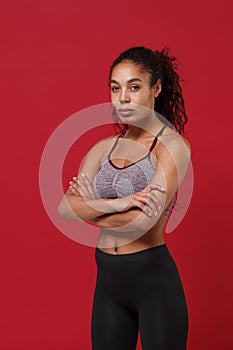 Beautiful young african american sports fitness woman in sportswear posing working out isolated on red background studio