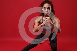Beautiful young african american sports fitness woman in sportswear working out  on red background. Sport