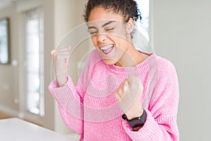 Beautiful young african american woman with afro hair excited for success with arms raised celebrating victory smiling