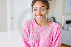 Beautiful young african american woman with afro hair smiling looking side and staring away thinking