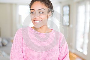 Beautiful young african american woman with afro hair smiling looking side and staring away thinking