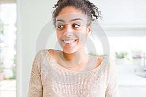 Beautiful young african american woman with afro hair smiling looking side and staring away thinking