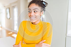 Beautiful young african american woman with afro hair smiling looking side and staring away thinking