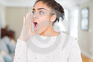 Beautiful young african american woman with afro hair wearing casual sweater shouting and screaming loud to side with hand on
