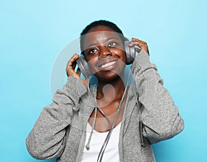 Beautiful Young African American woman listen to music over blue background.