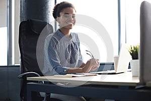 Beautiful young african american woman is sitting in the office and looking at camera