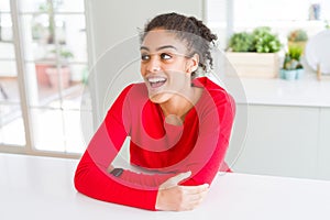 Beautiful young african american woman smiling cheerful leaning on the table comfortable