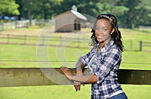 Beautiful young African American woman standing along farm fence - rural