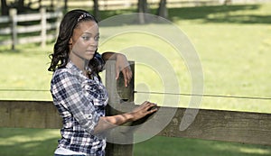 Beautiful young African American woman standing along farm fence - rural