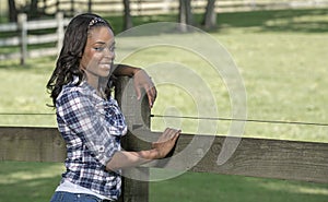 Beautiful young African American woman standing along farm fence - rural