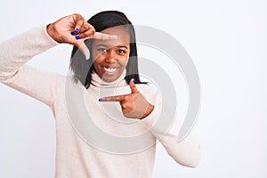 Beautiful young african american woman wearing turtleneck sweater over isolated background smiling making frame with hands and
