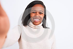 Beautiful young african american woman wearing turtleneck sweater taking a selfie with a happy face standing and smiling with a