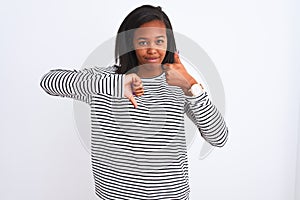 Beautiful young african american woman wearing winter sweater over isolated background Doing thumbs up and down, disagreement and