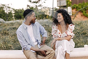 Beautiful young african friends have interesting conversation walking outdoors in summer.