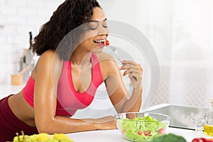 Beautiful young african girl eating vegetable salad