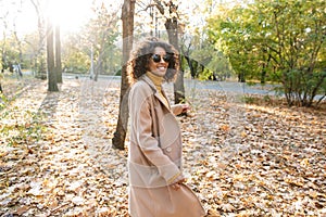 Beautiful young african happy woman walking outdoors in a spring park