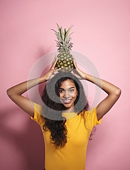 Beautiful African woman holding a pineapple on her head