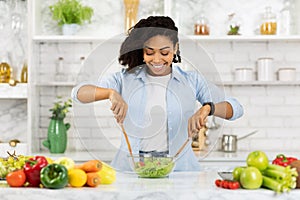 Beautiful young african woman preparing vegetable salad