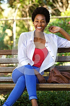 Beautiful young african woman sitting on a park bench