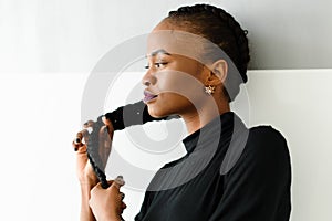 Beautiful young african woman touching her long hair on studio background