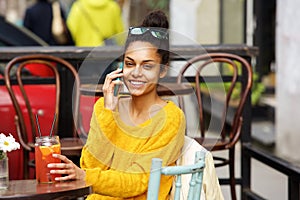 Beautiful young african woman using cell phone at cafe