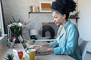 Beautiful young afro business woman working with laptop sitting in the office at home