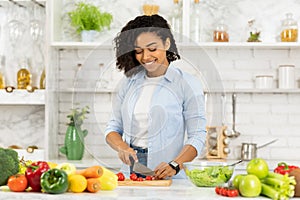 Beautiful young afro woman preparing vegetable salad