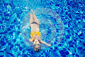 Beautiful young armless woman training to swim in pool at tropical resort