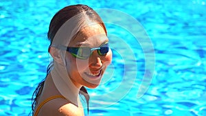 Beautiful young armless woman training to swim in pool at tropical resort