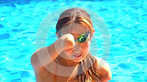 Beautiful young armless woman training to swim in pool at tropical resort,she puts glasses on eyes for protect from