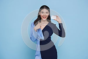 Beautiful young Asian business woman smiling, showing, presenting mockup credit card for online payment isolated on blue
