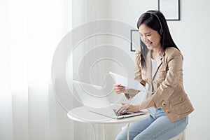 Beautiful young asian business woman using laptop computer working from home for video conference online.