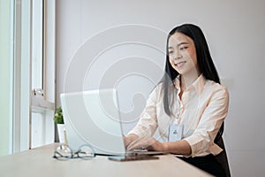 A beautiful young Asian businesswoman or female officer is working on her laptop in the office