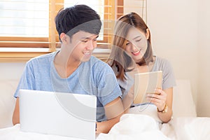 Beautiful young asian couple cheerful freelance working with man using laptop and woman using tablet on couch