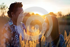 Beautiful young Asian Couple enjoying nature on field grass meadow at sunrise