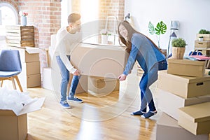 Beautiful young asian couple looking happy, holding a big cardboard box smiling excited moving to a new home