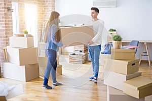 Beautiful young asian couple looking happy, holding a big cardboard box smiling excited moving to a new home