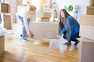 Beautiful young asian couple looking happy, holding a big cardboard box smiling excited moving to a new home