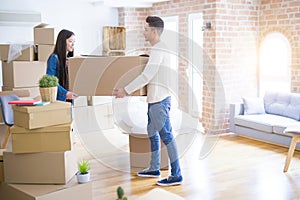 Beautiful young asian couple looking happy, holding a big cardboard box smiling excited moving to a new home